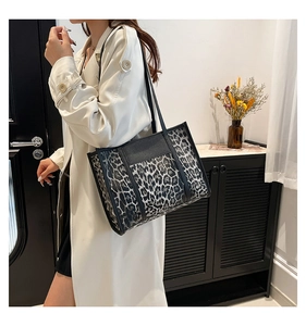 Side view of a large leopard print tote bag styled on a model in a modern room