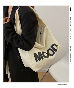 Detail of beige canvas tote bag with MOOD letter print and side zipper pocket