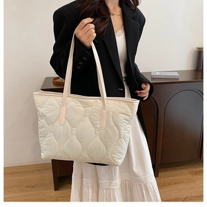 Quilted tote bag detail showing wavy stitching and beige nylon texture on shoulder