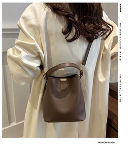Dettaglio della borsa a secchiello marrone con logo FASHION e texture in pelle liscia
