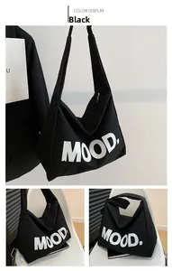 Detail view of black canvas tote bag with white MOOD text and zipper closure