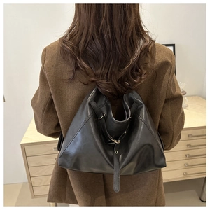 Detailed back view of a minimalist black leather tote bag worn with a brown blazer