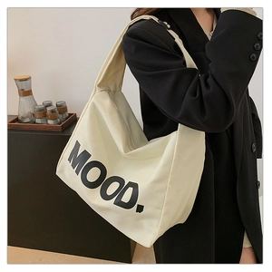 Dettaglio della grande borsa tote in tela beige con stampa MOOD nera e tracolla