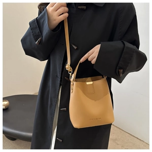 Detail of ginger yellow bucket bag with fashion lettering and metal buckle on black coat