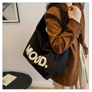 Detail shot of the black canvas tote bag with a large white MOOD letter print design
