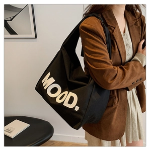 Dettaglio della borsa tote in tela nera con stampa del testo MOOD per un look retrò