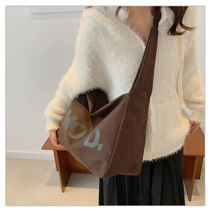 Detail of a brown canvas tote bag with large MOD. lettering and thick wide shoulder strap