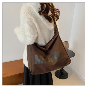 Vista dettagliata di una grande borsa tote marrone in tela con scritta MOOD sul retro
