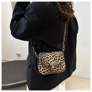 Détail du sac bandoulière léopard avec fermoir doré porté par un mannequin