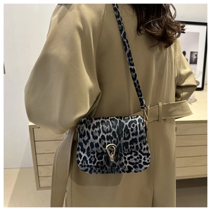 Détail du sac léopard avec boucle en métal doré en fer à cheval porté sur un trench-coat