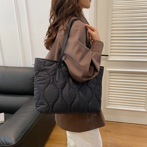 Grande borsa tote nera trapuntata con cuciture a onda e manici lunghi per il pendolarismo