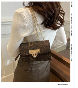 Rear view of brown letter print crossbody bag with gold heart lock on a model