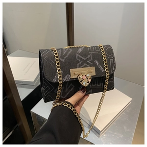 Detail of floral heart-shaped gold lock and chain on black crossbody bag with logo print