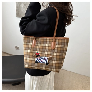 Détail de la broderie teckel sur un sac cabas à carreaux porté à l'épaule avec style