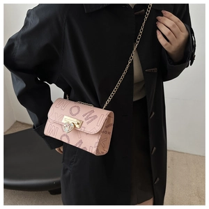Detail of pink crossbody bag with letter prints and rhinestone heart-shaped metal buckle