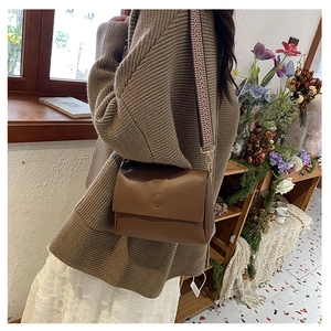 Detail of dark brown flap shoulder bag with retro geometric patterned wide strap