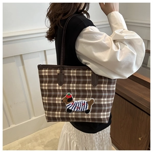 Détail du sac cabas à carreaux marron avec écusson de chien de dessin animé et petit chapeau