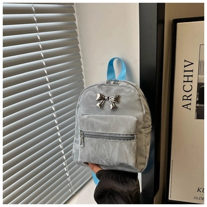 Close-up of light grey nylon mini backpack with silver metal bow and blue handle
