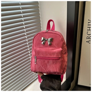Detail of hot pink nylon backpack featuring a polished silver metal bow ornament