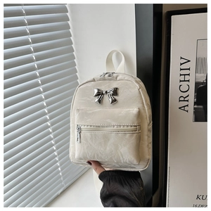 Détail du mini sac à dos blanc cassé avec texture plissée et nœud en métal argenté