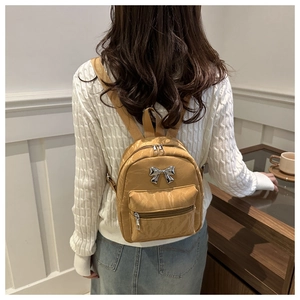 Caramel bow backpack detail showing crinkled faux leather texture and silver bow detail