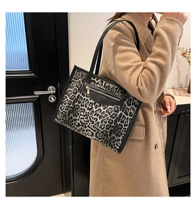 Detailed view of leopard print tote bag with black zip pocket and shoulder straps
