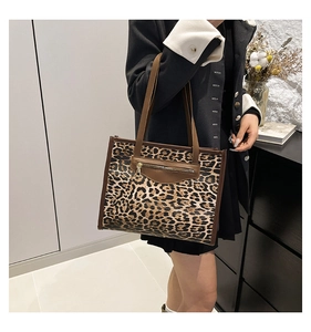 Detail of leopard print tote bag with brown leather handles and a front zipper pocket