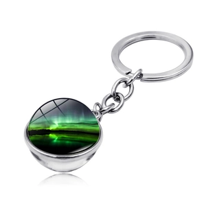 Detail of silver aurora keychain with glass cabochon showing green northern lights landscape