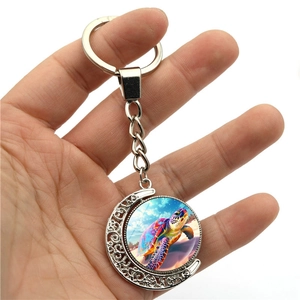 Rotating turtle keychain with moon-shaped silver hollow frame and colorful glass sea turtle