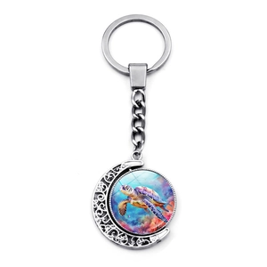 Detail of silver turtle spinning keychain with half-moon frame and glass sea artwork
