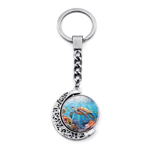 Detail of a rotating sea turtle keychain with intricate hollowed vine patterns in silver finish