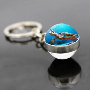 Porte-clés tortue de mer avec pendentif en verre double face sur fond noir réfléchissant