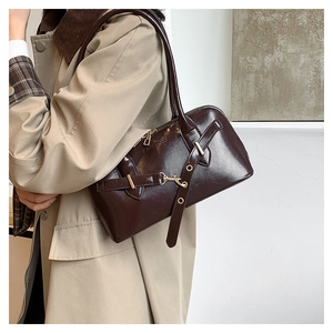 Detail of oil-wax leather shell bag showing metallic buckle straps and fashion logo