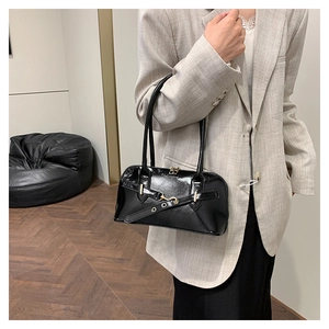 Detail of glossy black patent leather bag with metal eyelet strap and fashion embossed logo