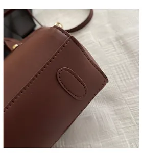 Vue détaillée des coutures du cuir marron foncé et de la texture lisse d'un cabas
