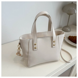 Détail du sac cabas en cuir crème avec rivets dorés et finitions métalliques lisses