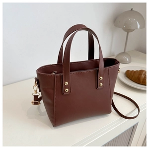 Vue détaillée d'un sac cabas marron avec rivets dorés sur un bureau blanc élégant