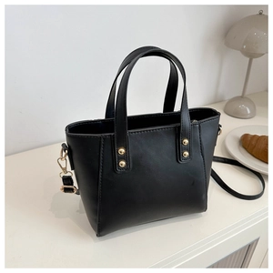 Détail d'un sac cabas noir en simili cuir avec boucles dorées et bandoulière amovible