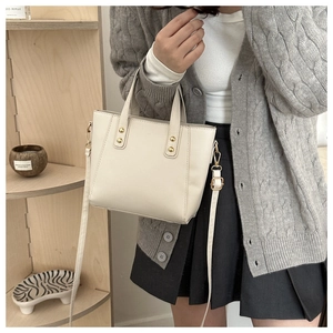 Détail d'un sac à main beige en cuir PU avec clous dorés et bandoulière réglable pratique