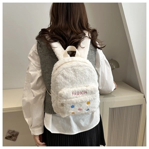 Détail d'un sac à dos blanc en peluche avec broderie FASHION et boutons colorés
