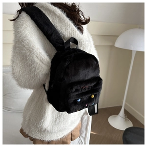 Détail d'un sac à dos noir en peluche avec broderie rouge et perles décoratives