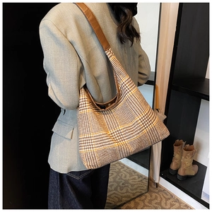 Detail of hobo shoulder bag with houndstooth pattern and leather strap in side view