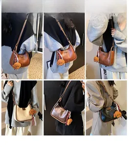 Detail showing plush bear charm and striped scarf on textured faux leather shoulder bag