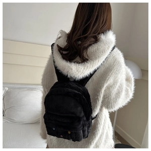 Close-up of black plush backpack with colorful polka dots on soft faux fur material