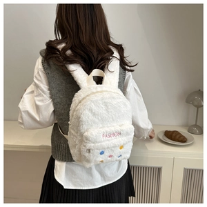 Gros plan du sac à dos en peluche blanche avec oreilles de lapin et boutons colorés