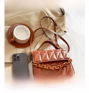Vue détaillée du sac matelassé marron avec chaîne orange sur une veste de costume