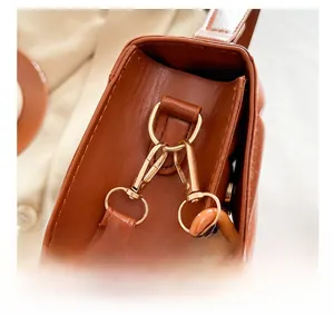 Gros plan des boucles métalliques dorées et de la quincaillerie sur un sac en cuir marron