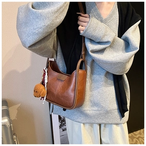Close-up of brown PU leather shoulder bag with cute teddy bear charm and fashion label
