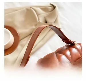 Détail de la poignée large en cuir marron et de l'anneau en métal du sac matelassé