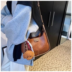 Brown lychee leather shoulder bag with FASHION logo and teddy bear charm on model